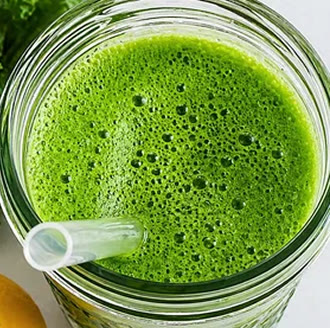 Batido verde casero en un vaso de cristal con pajita